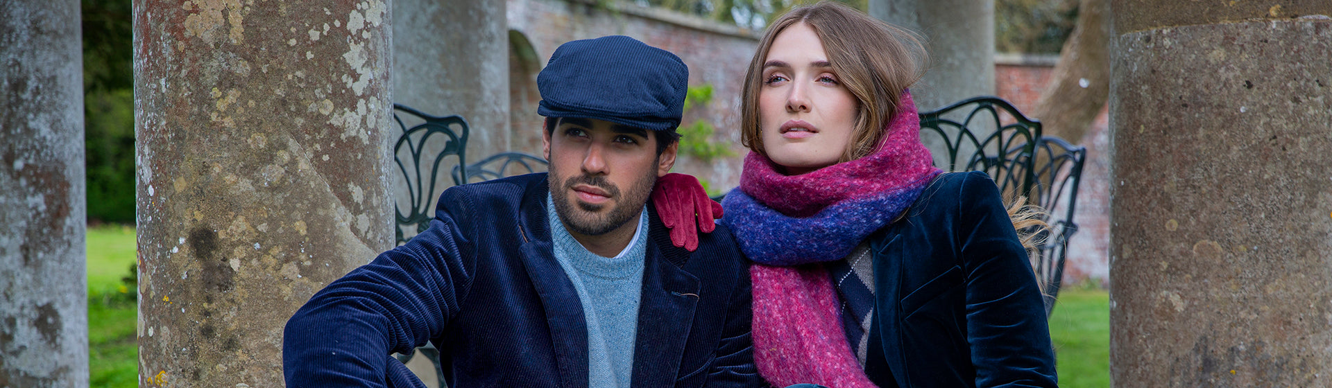 Woman wearing a scarf and suede gloves sat with a man wearing a flat cap at a country estate