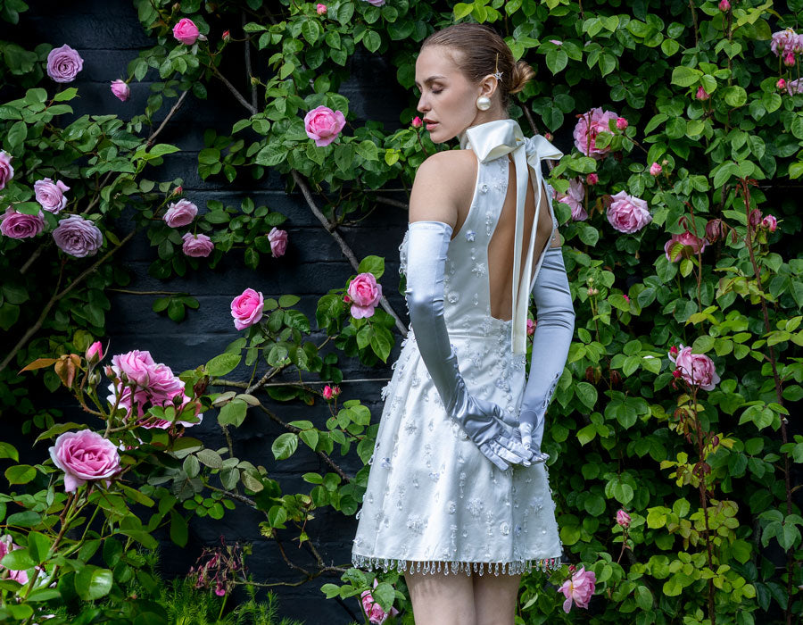 Woman in a white dress and long satin gloves in silver with a floral background