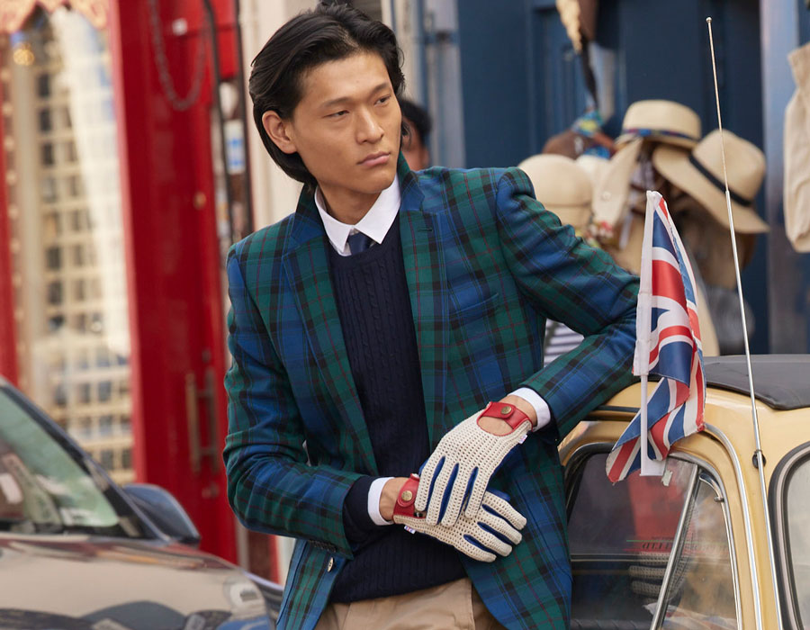 Man wearing heritage leather driving gloves leaning on a car in the city