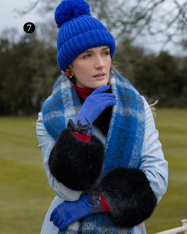 Woman wearing velour lined faux suede gloves with trim and bow in cobalt