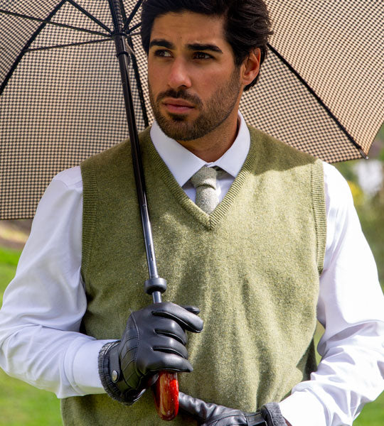 Man wearing leather driving gloves in black holding an umbrella whilst on a stroll