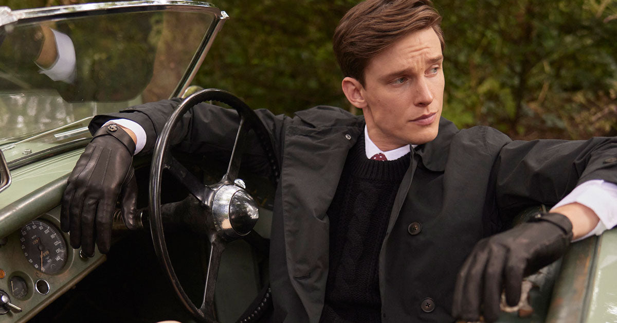 Man in formal attire leaning on a vintage car wearing heritage leather driving gloves in black