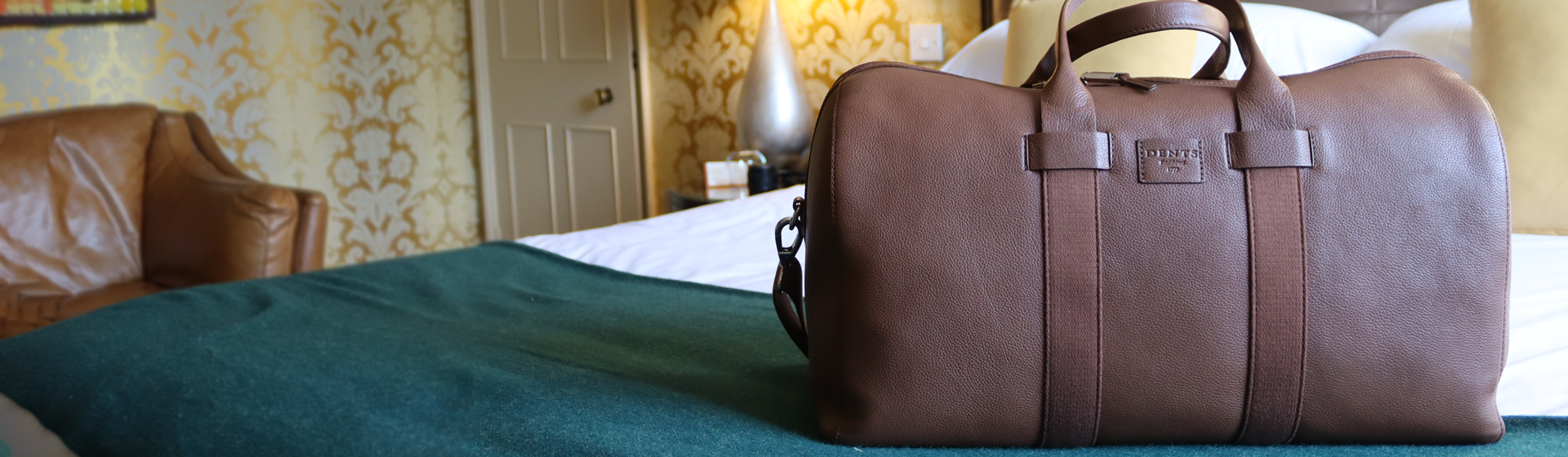 Men's leather bag laid out on bed