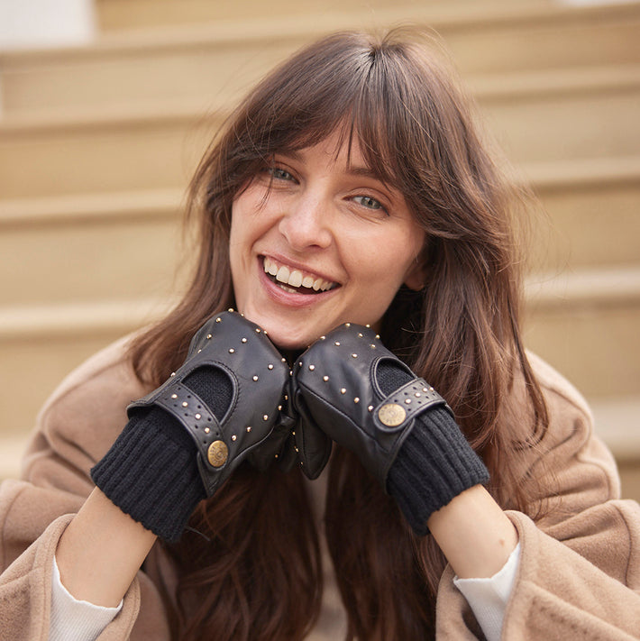 Woman wearing black leather gloves with studs sat on a doorstep in the city