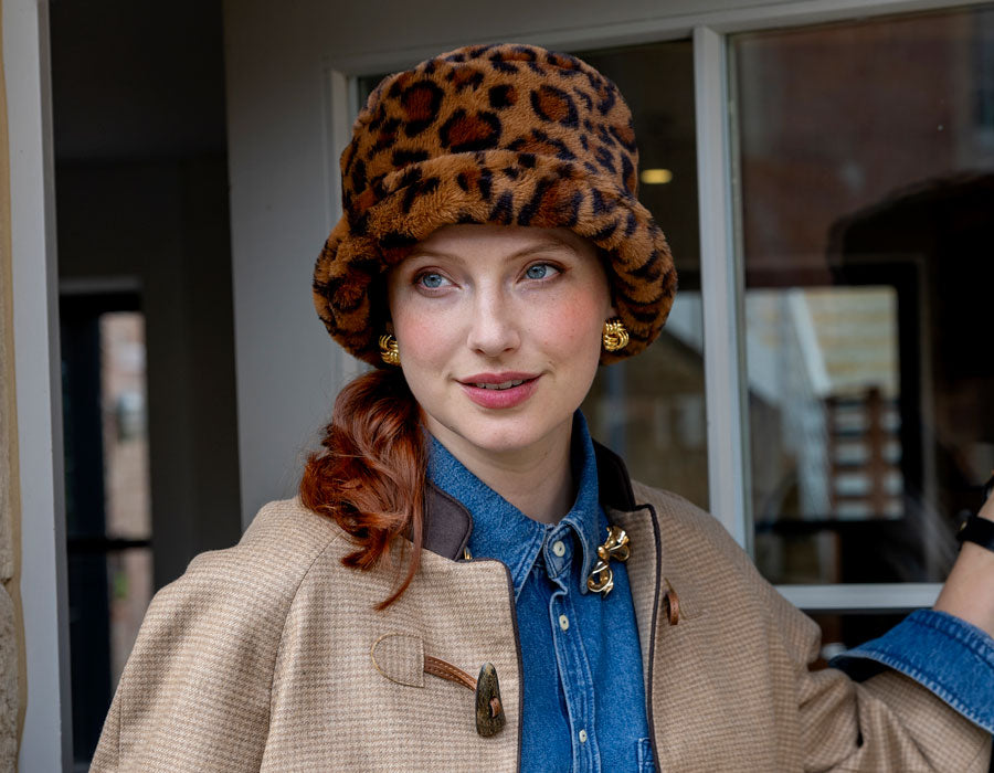 Woman wearing a leopard print bucket hat leaving through a door outside