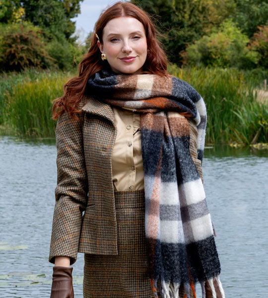 Woman wearing a check blanket scarf whilst walking near a lake